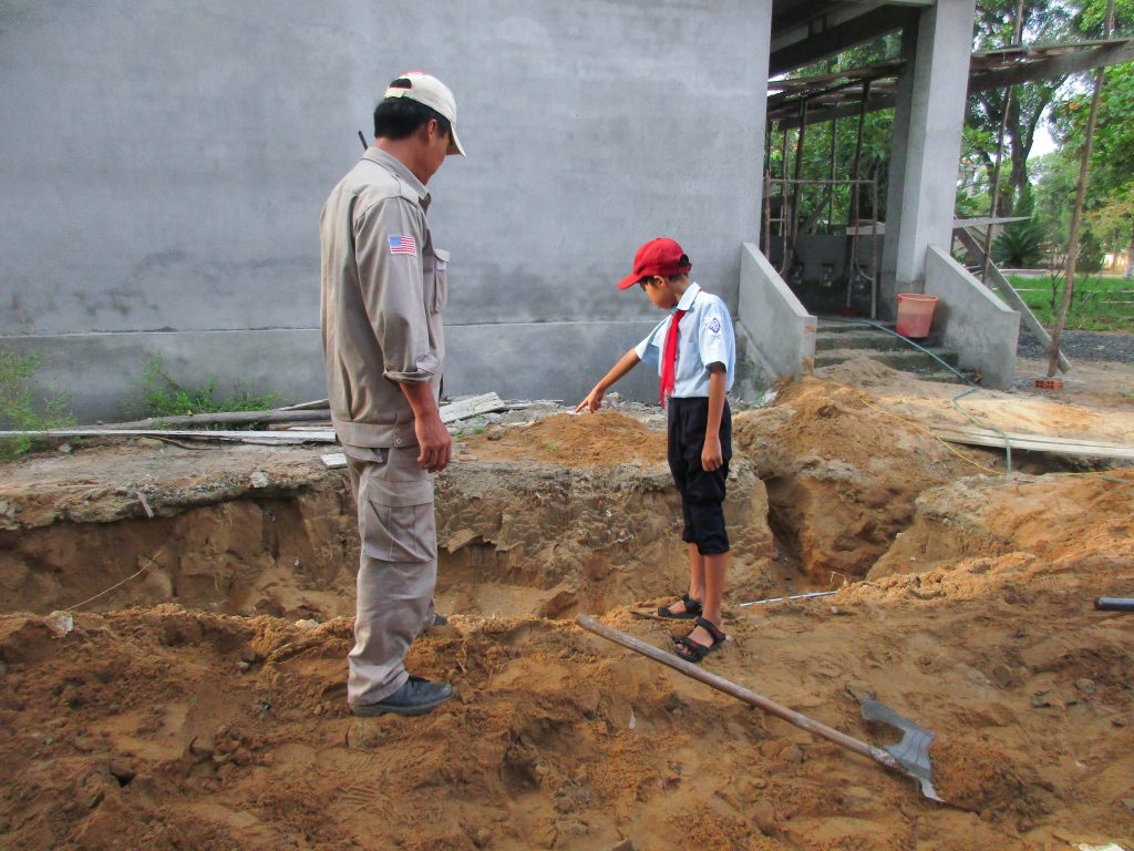 A schoolboy showing EOD Team Leader Le Xuan Tung the location where they took the soil.